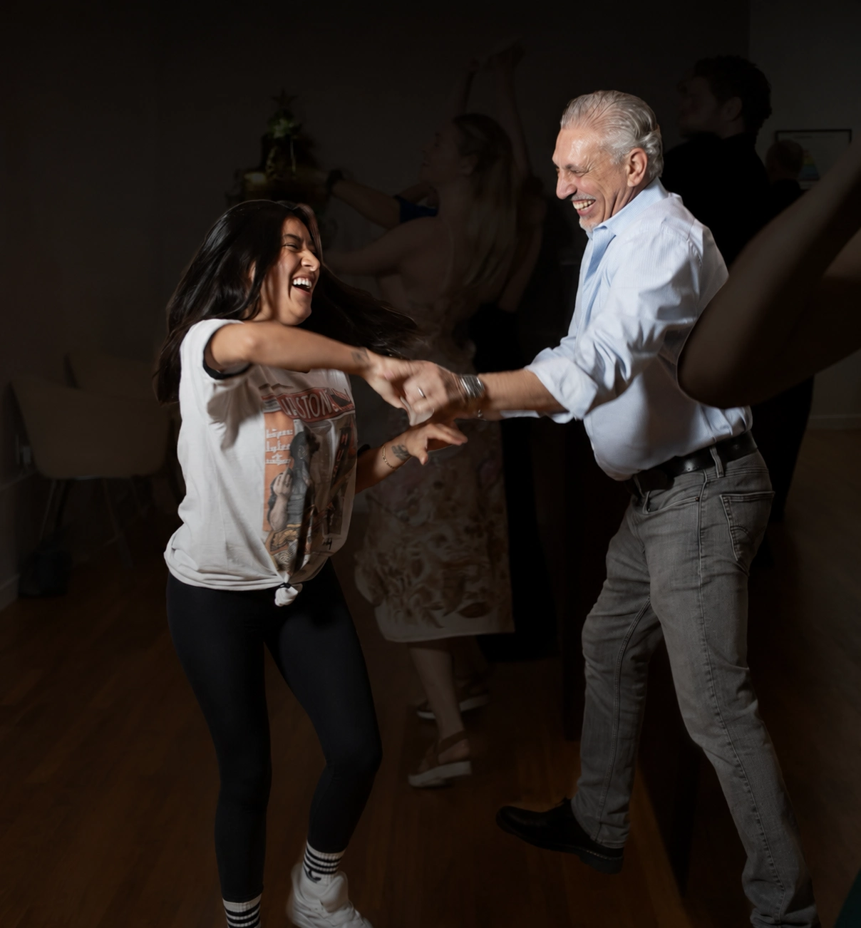 Two smiling partners enjoy a lively spin during Couples Dance Classes in Playa del Rey, sharing a fun social dance moment in a welcoming studio surrounded by other dancers.