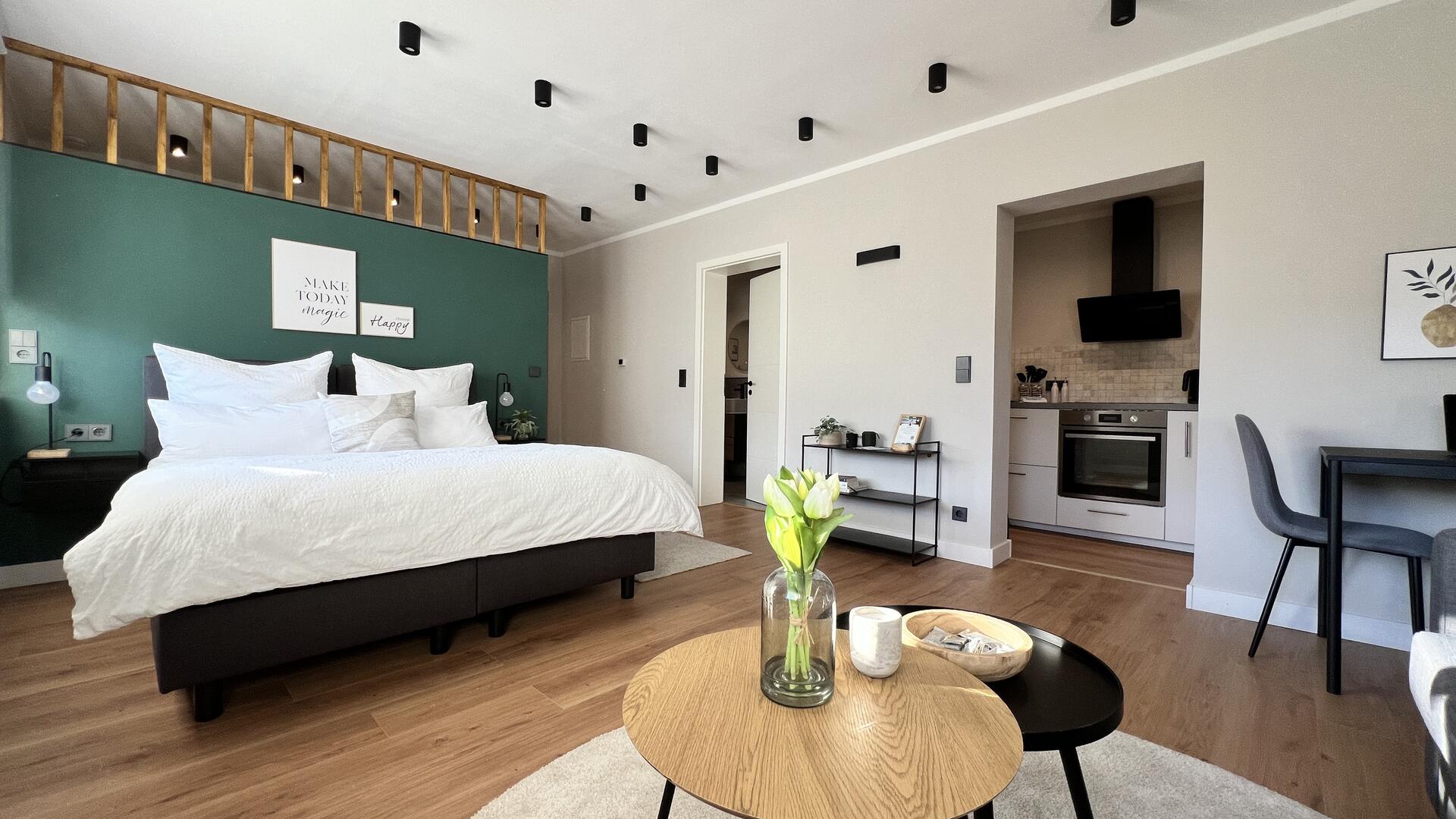 Aufnahme Wohnraum Apartment mit Bett und Aussicht in die Küche