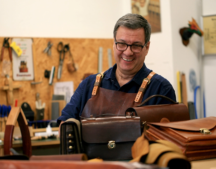 Michael Ehlers in seiner Werkstatt. Auf dem Tisch vor ihm liegen Taschen.