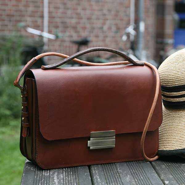 Taschenmodell 2 steht auf einem Tisch neben einem Strohhut