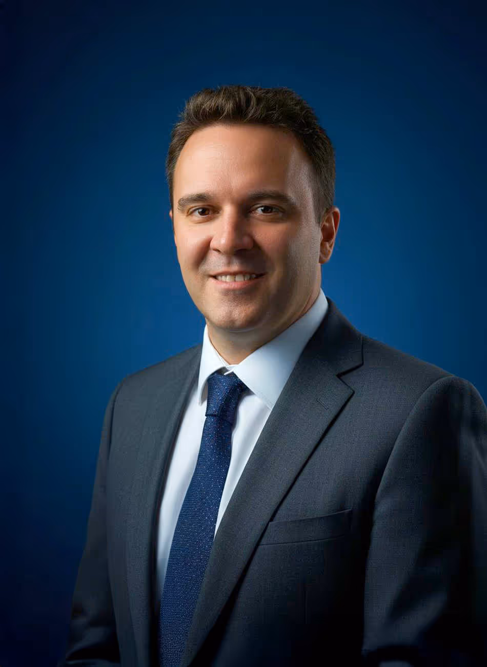 Maven Radd lawyer, Ian Fairclough - smiling man in a formal suit and tie against a blue background, conveying professionalism and confidence.