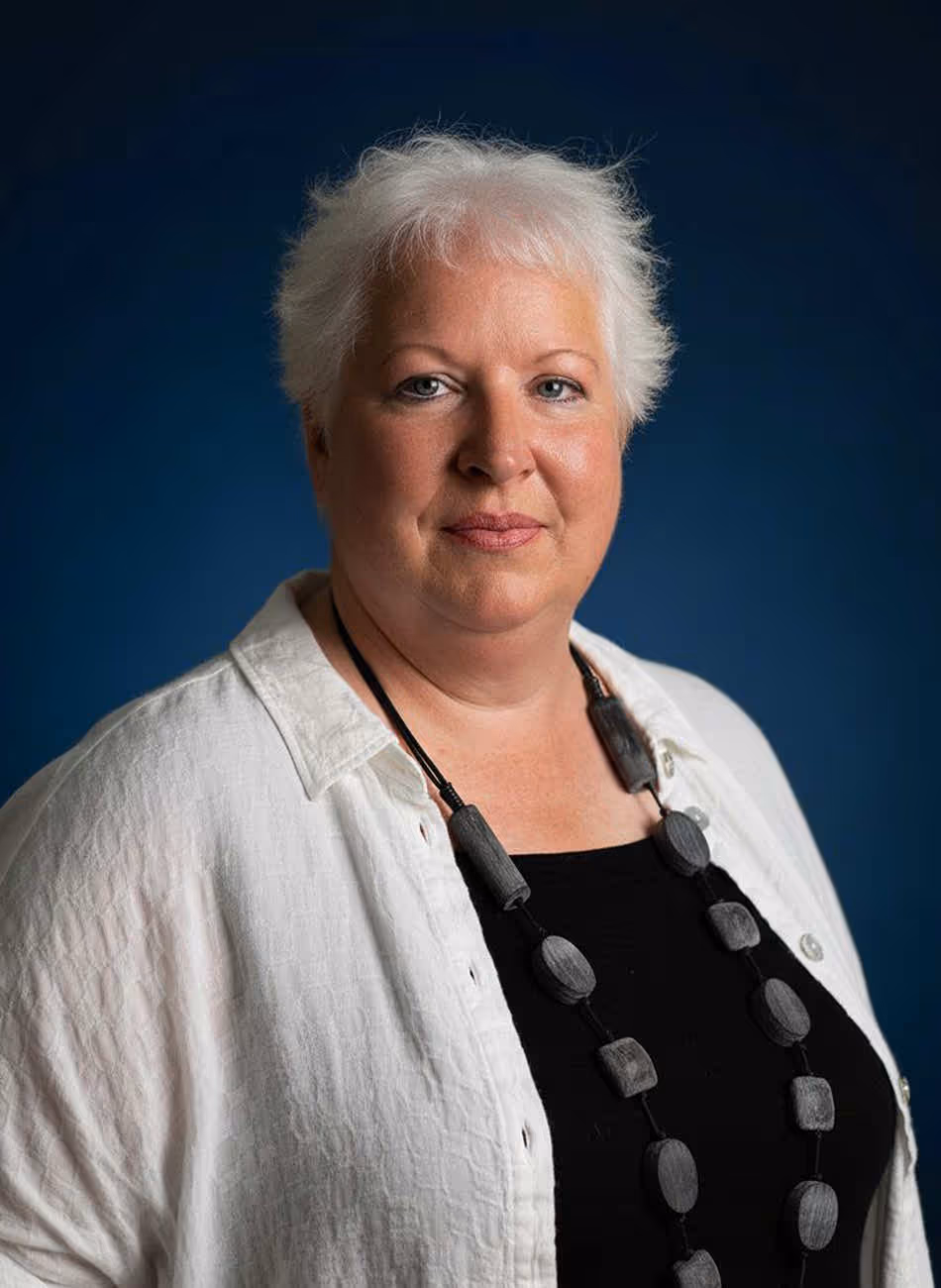 Maven Radd lawyer, Gillian Hogarth - with short, white hair, wearing a white blouse and a dark necklace, against a dark blue background.