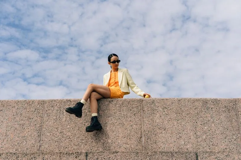 Woman in an orange dress sitting in a wall.