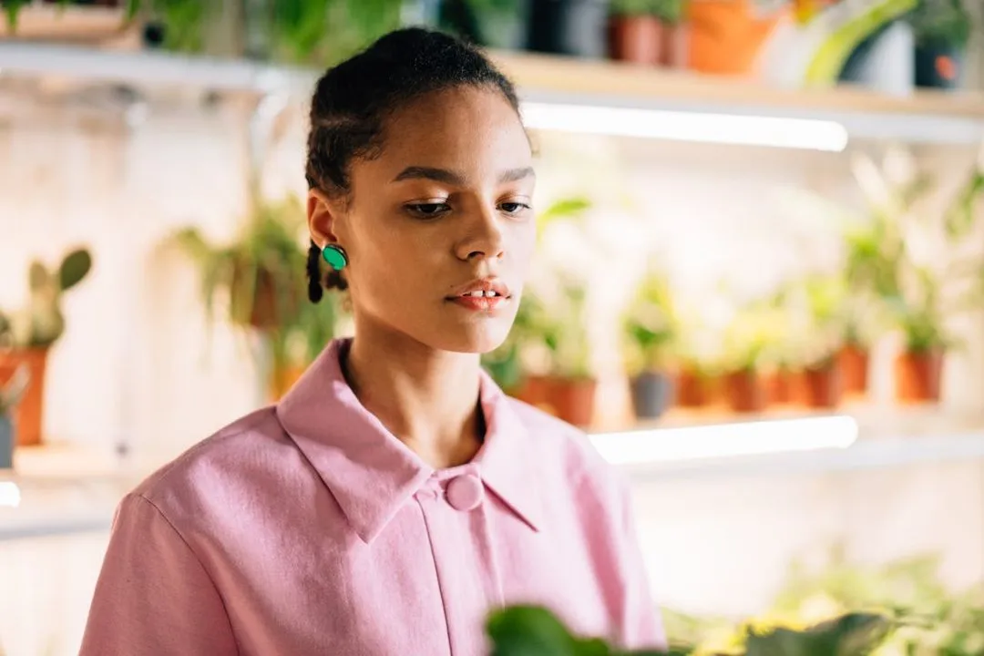 Woman holding a plant and looking down.