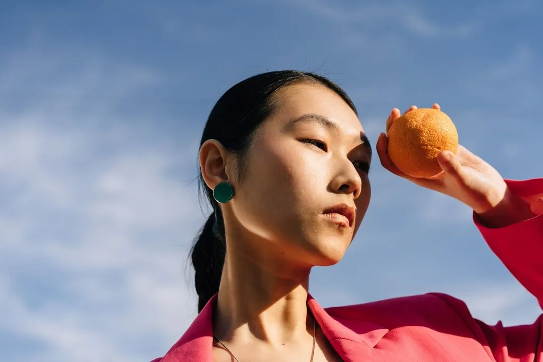 Woman in a pink suit holding an orange.