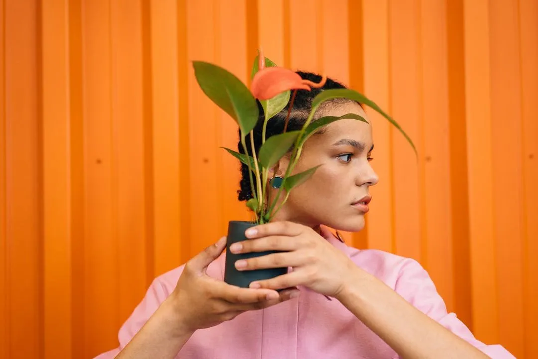 Woman covering her face with a plant.