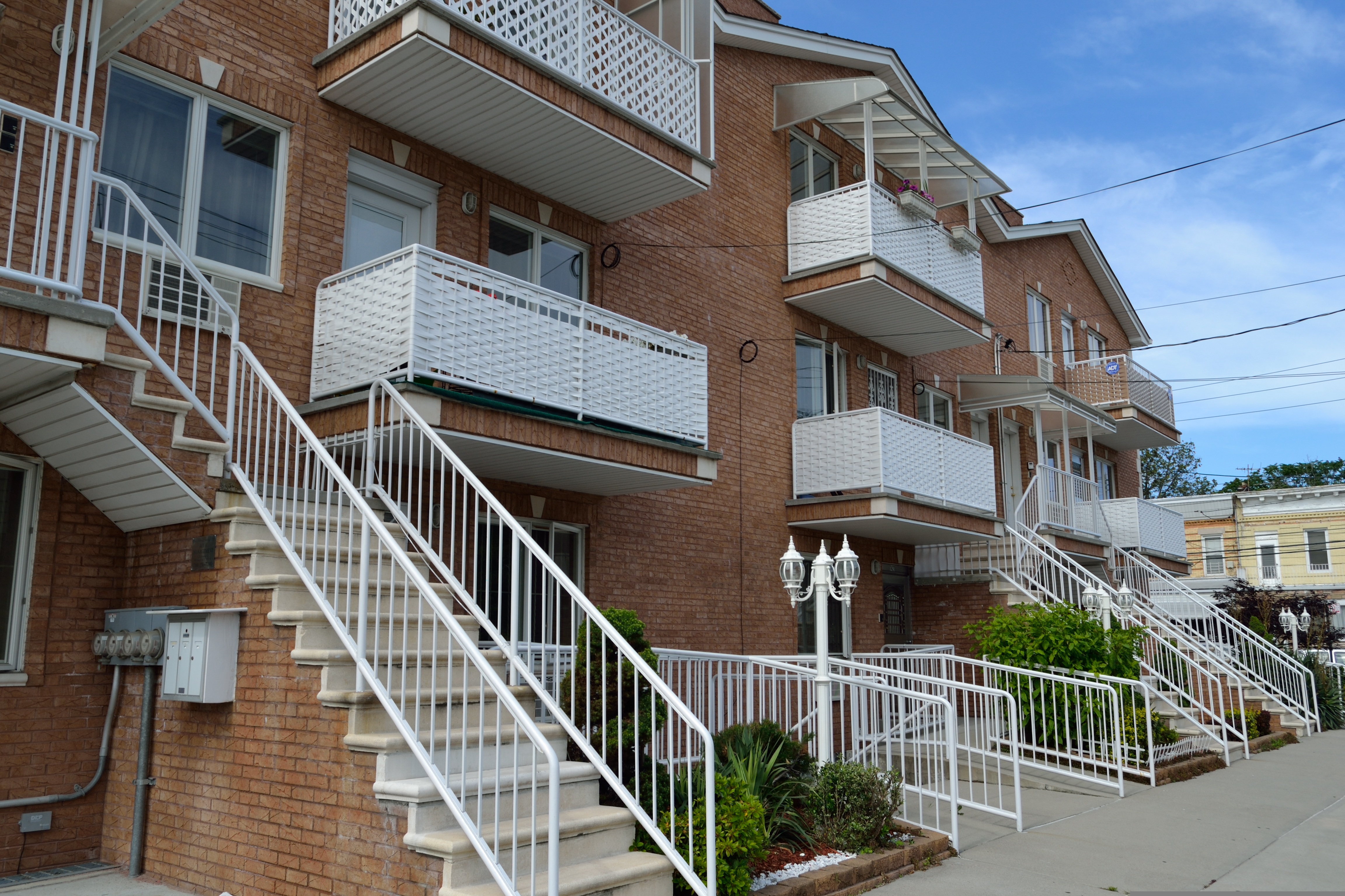 Exterior of a multi-family apartment building with individual entrances and balconies.