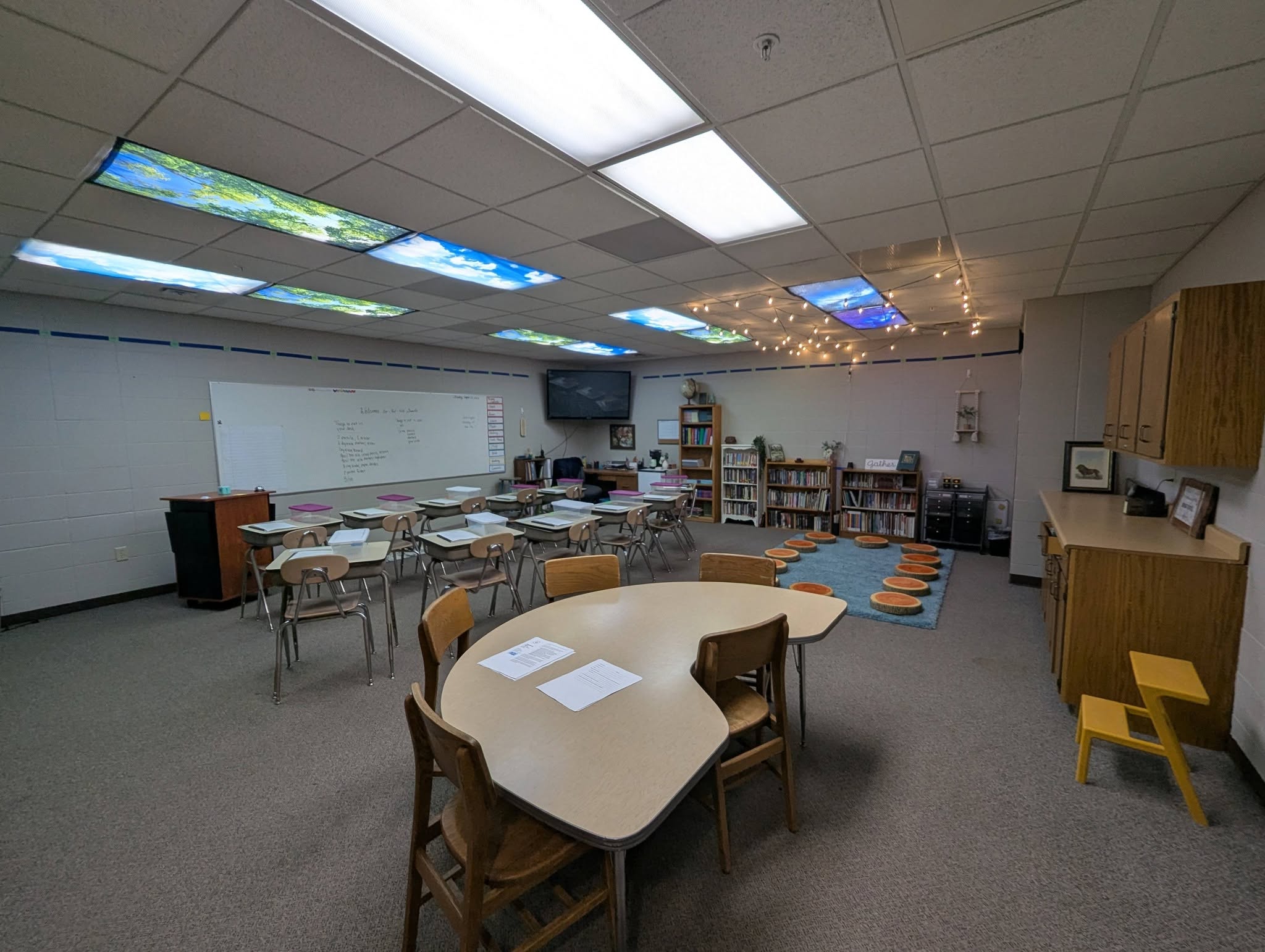 Teacher assisting two students inside a classroom.