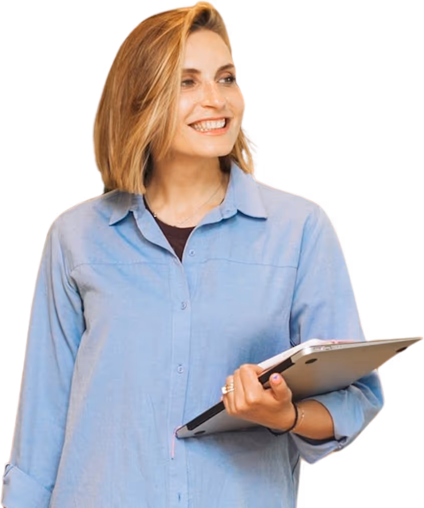 Une femme blonde en chemise bleu, tenant un macbook dans sa main droite. Elle regarde vers sa gauche avec un grand sourire.