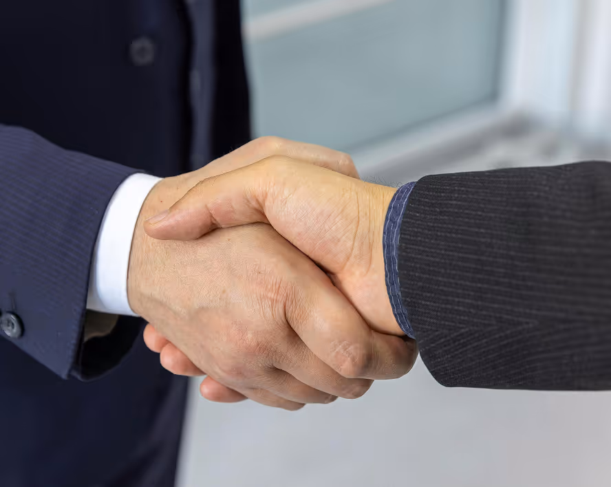 Deux mains serrées, symbolisant un accord ou une réunion d'affaires, sur fond flou.