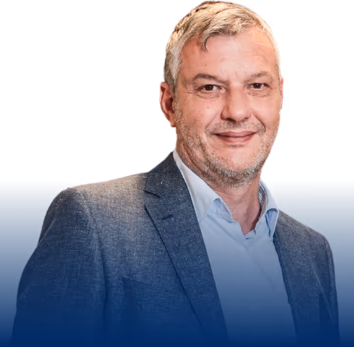 Une personne souriante vêtue d'un blazer gris pose devant un fond sombre dégradé, dégageant une apparence professionnelle.