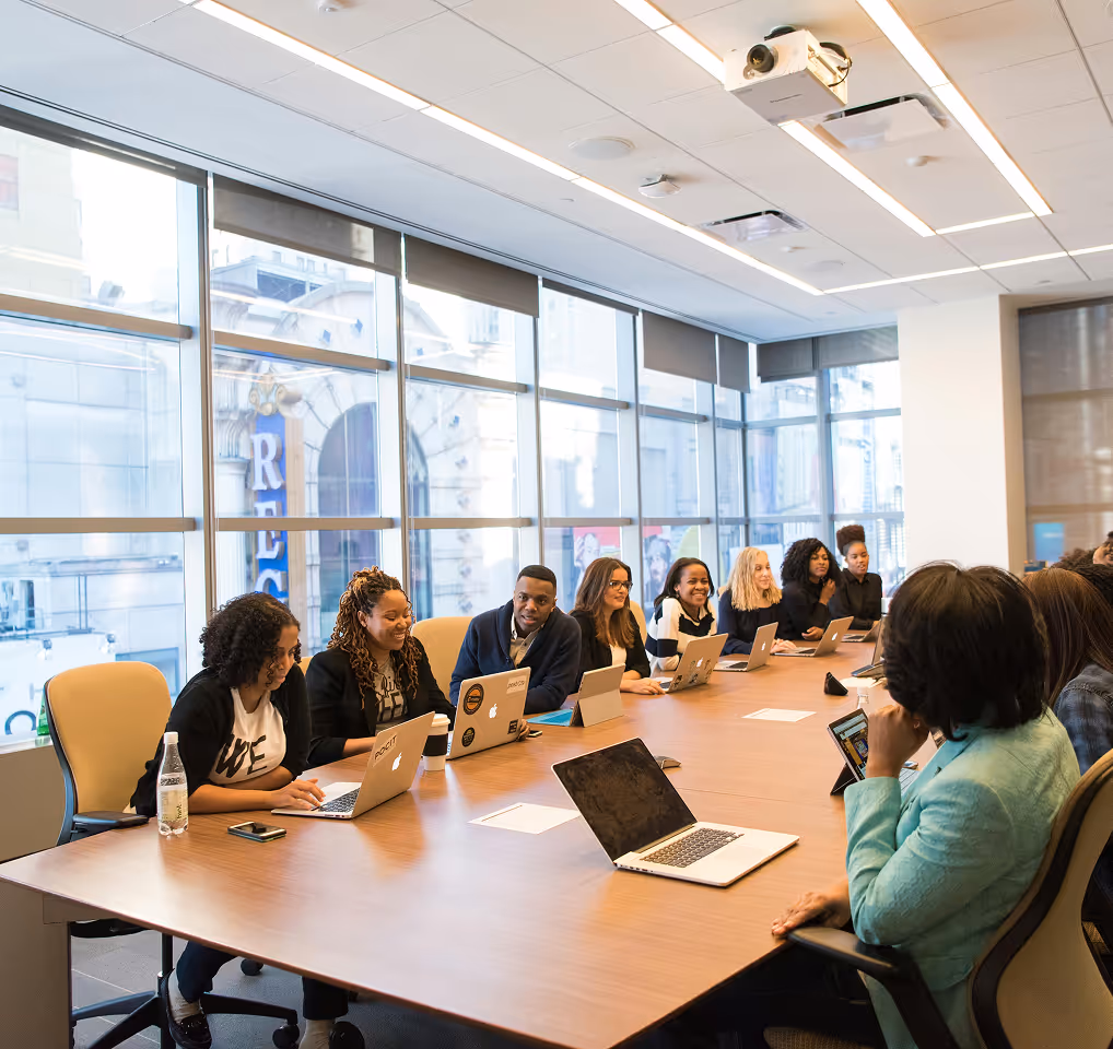 Un groupe diversifié de professionnels travaillant autour d'une table de conférence avec des ordinateurs portables, participant à une réunion et collaborant entre eux.