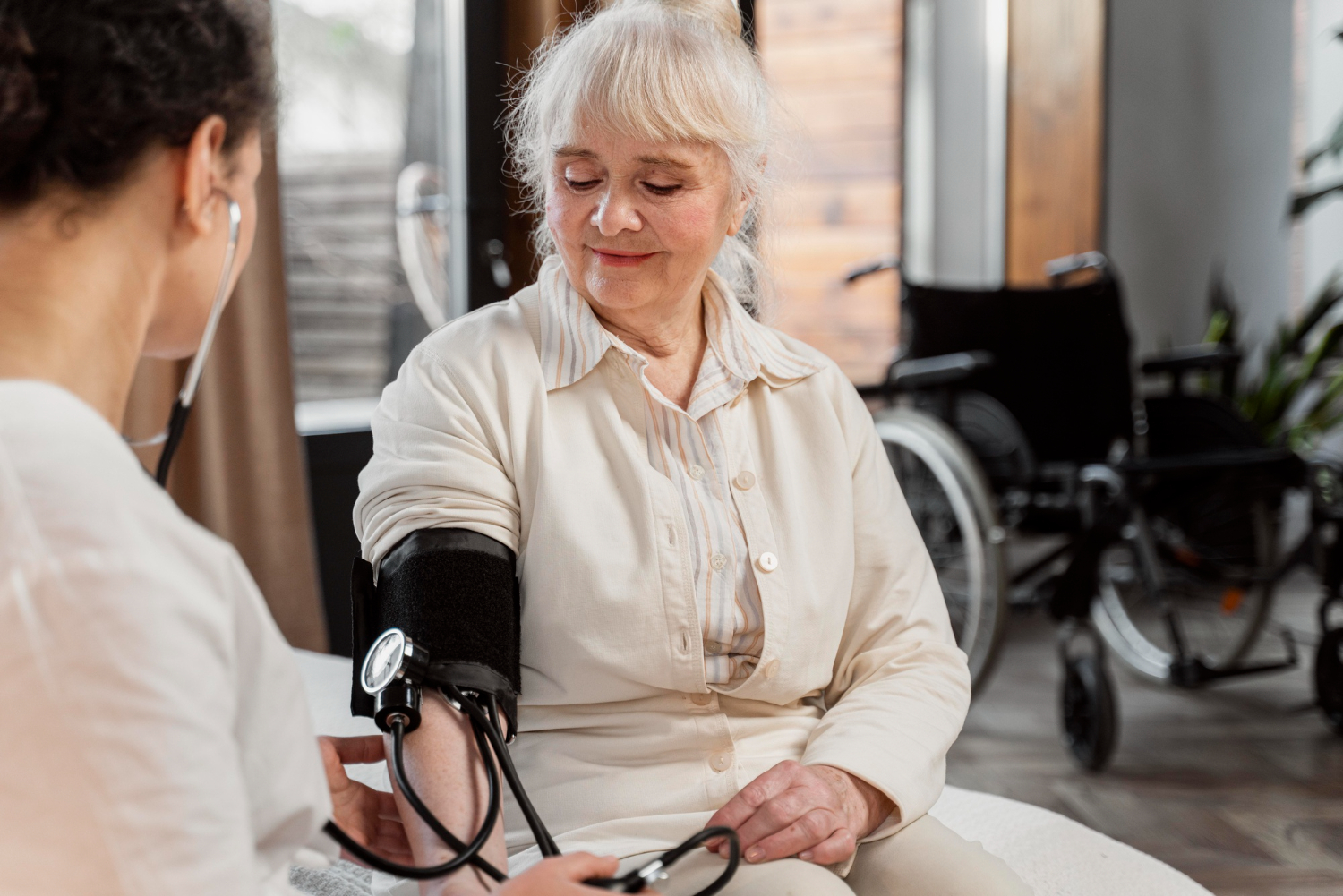 Eine Ärztin zeigt einer im Rollstuhl sitzenden Patientin etwas auf einem Tablet, wobei beide Frauen traurig dreinschauen.