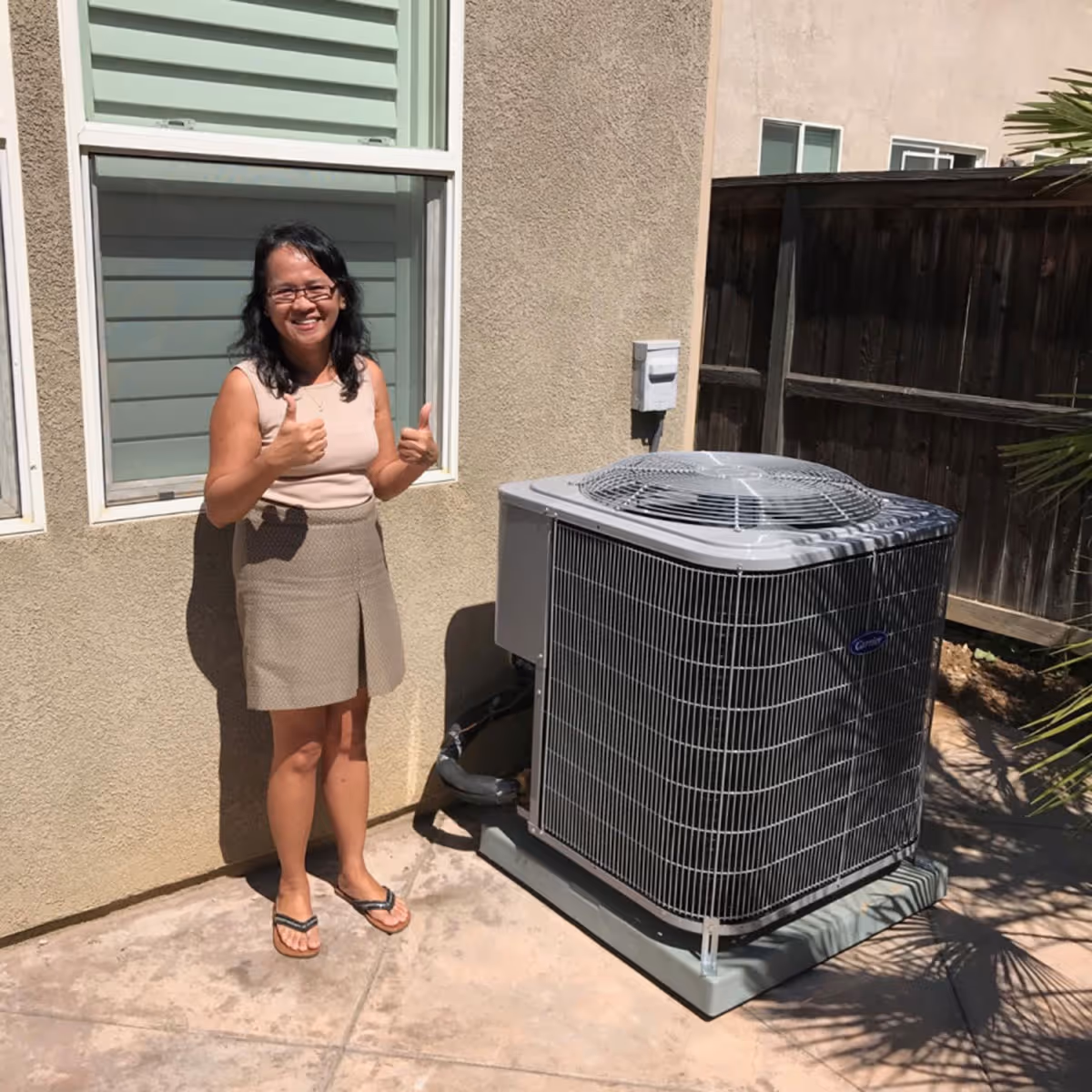 A happy, smiling customer stood next to their newly installed air conditioner.