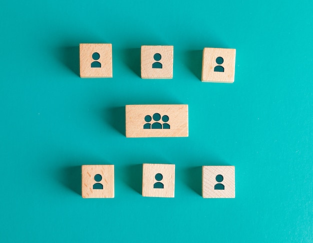 Fotografía sobre el concepto de estructura de gestión con iconos de personas en bloques de madera en mesa turquesa endecha plana.