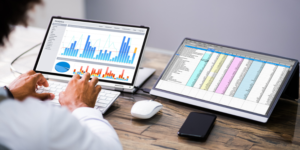 Professional analyzing data on a dual-monitor setup, with one screen displaying colorful analytics graphs and the other showing a detailed spreadsheet, exemplifying remote company data management.