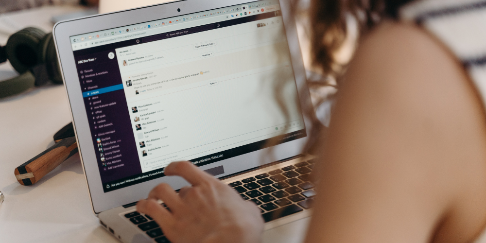Over-the-shoulder view of a professional using a laptop displaying an email client, indicative of remote company management and communication.