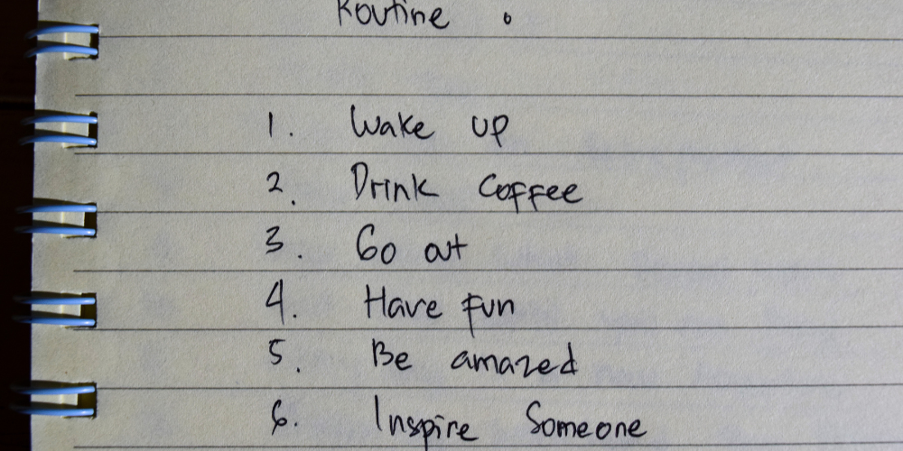 A handwritten list on a spiral notebook detailing a simple, inspirational daily routine, capturing the essence of a digital nomad's flexible lifestyle.