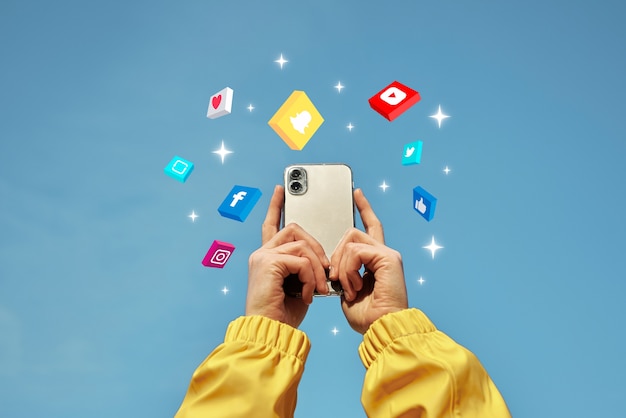 The image shows hands holding a smartphone with social media icons and engagement symbols floating around it, against a blue sky, illustrating social media management and performance monitoring.