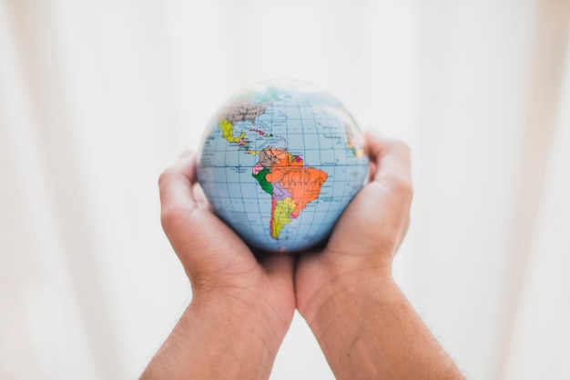 Two hands holding a small globe with a focus on the Americas, symbolizing a global perspective on the profession of SEO specialists, possibly reflecting on the international standards and salaries within the industry.