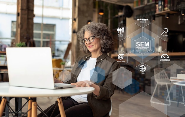 A professional woman with curly hair wearing glasses is smiling and working on a laptop in a modern office environment. There are digital marketing and SEO-related icons and graphics overlaying the image, suggesting a focus on Search Engine Marketing (SEM) strategies.