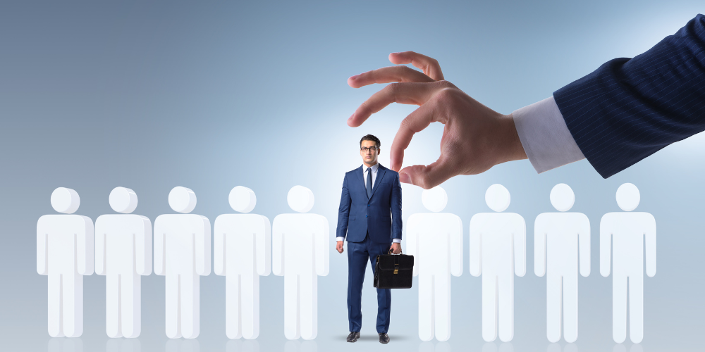 A large hand picking a businessman out from a lineup of white silhouetted figures, illustrating the selection of a candidate for a position or a special role in a company.