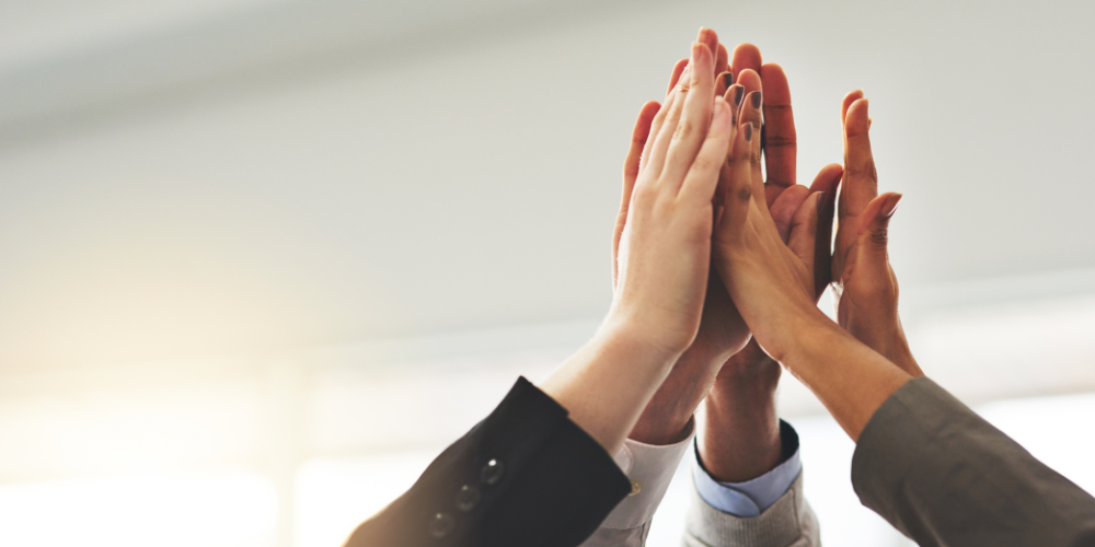 A group of professionals high-fiving in the air