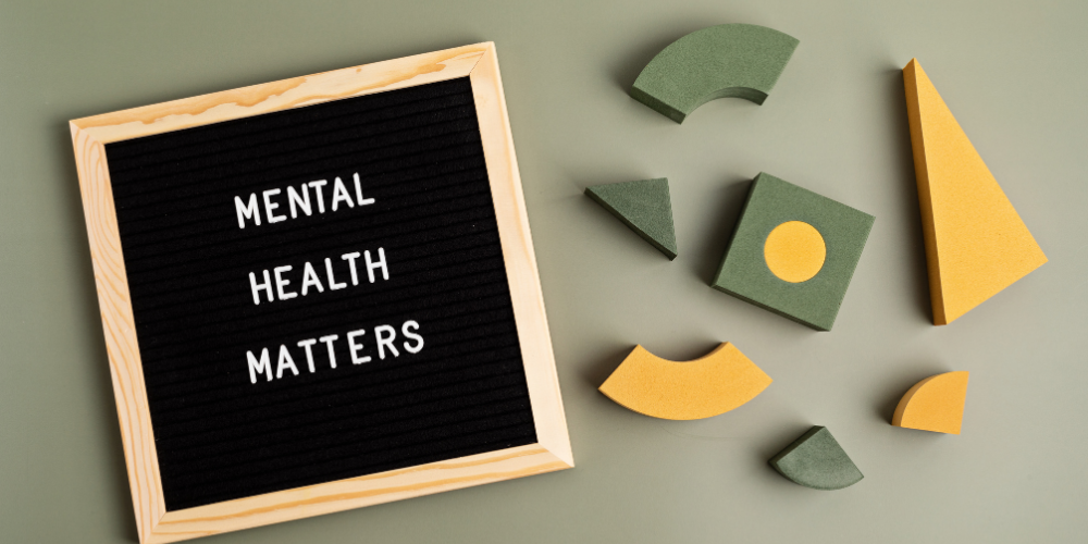A letter board with the phrase "MENTAL HEALTH MATTERS" displayed, accompanied by colorful geometric shapes scattered around it, symbolizing the importance of mental health awareness in a creative or work setting.