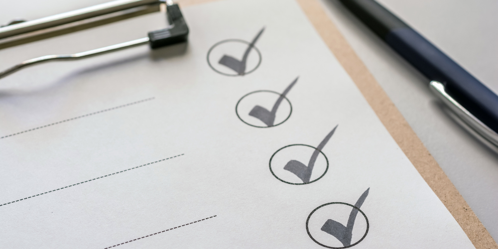 Close-up view of a clipboard with a checklist, showing items marked as complete with a black pen resting on the side.