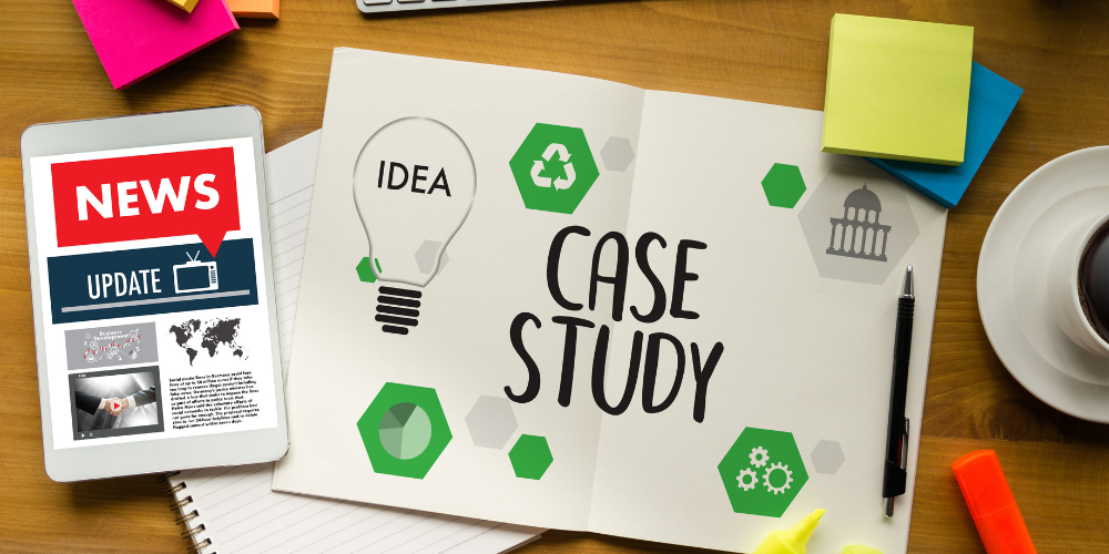 An open case study notebook with a light bulb graphic and 'CASE STUDY' text, surrounded by colorful sticky notes, a digital tablet displaying news updates, a pen, and a cup of coffee on a wooden desk