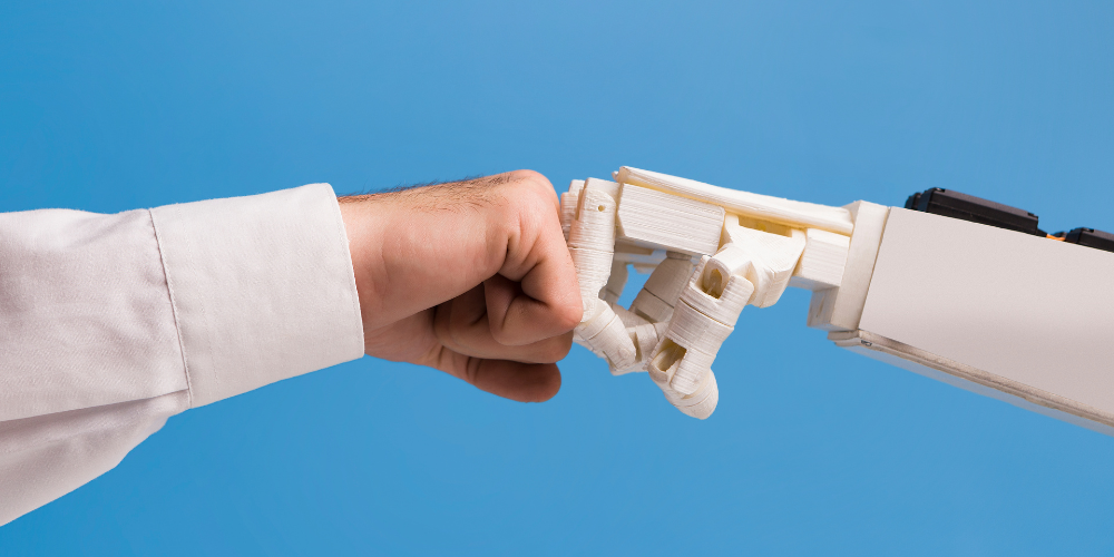 A human hand making a fist bump gesture with a robotic hand against a blue background.