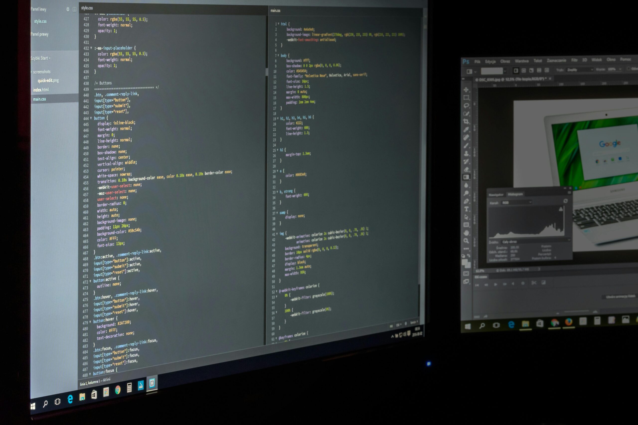 A darkened workspace illuminated by two computer monitors displaying a CSS code editor on the left and a graphic design application with a laptop image on the right
