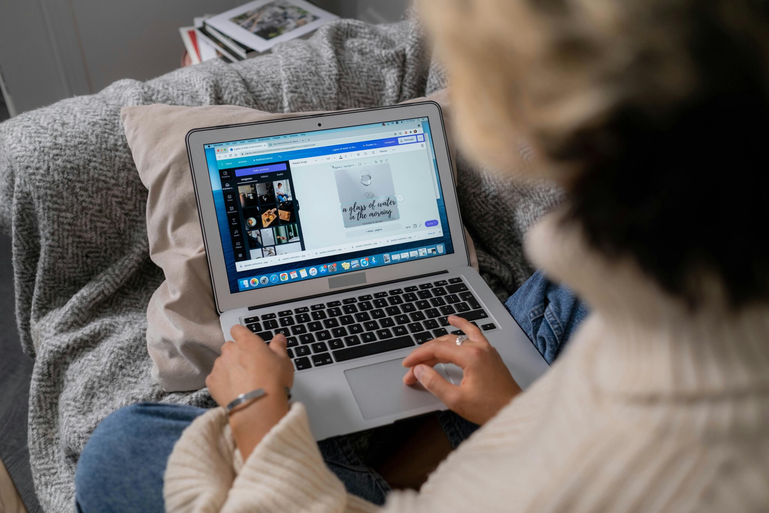 Over-the-shoulder view of a person using a laptop with social media graphics on the screen, seated comfortably with a cozy blanket.