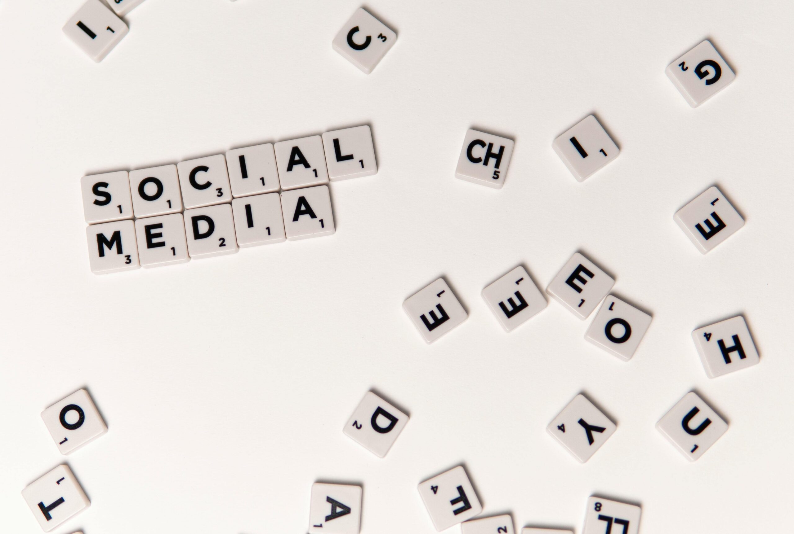 Letter tiles on a white surface spelling 'SOCIAL MEDIA' with scattered letters around.