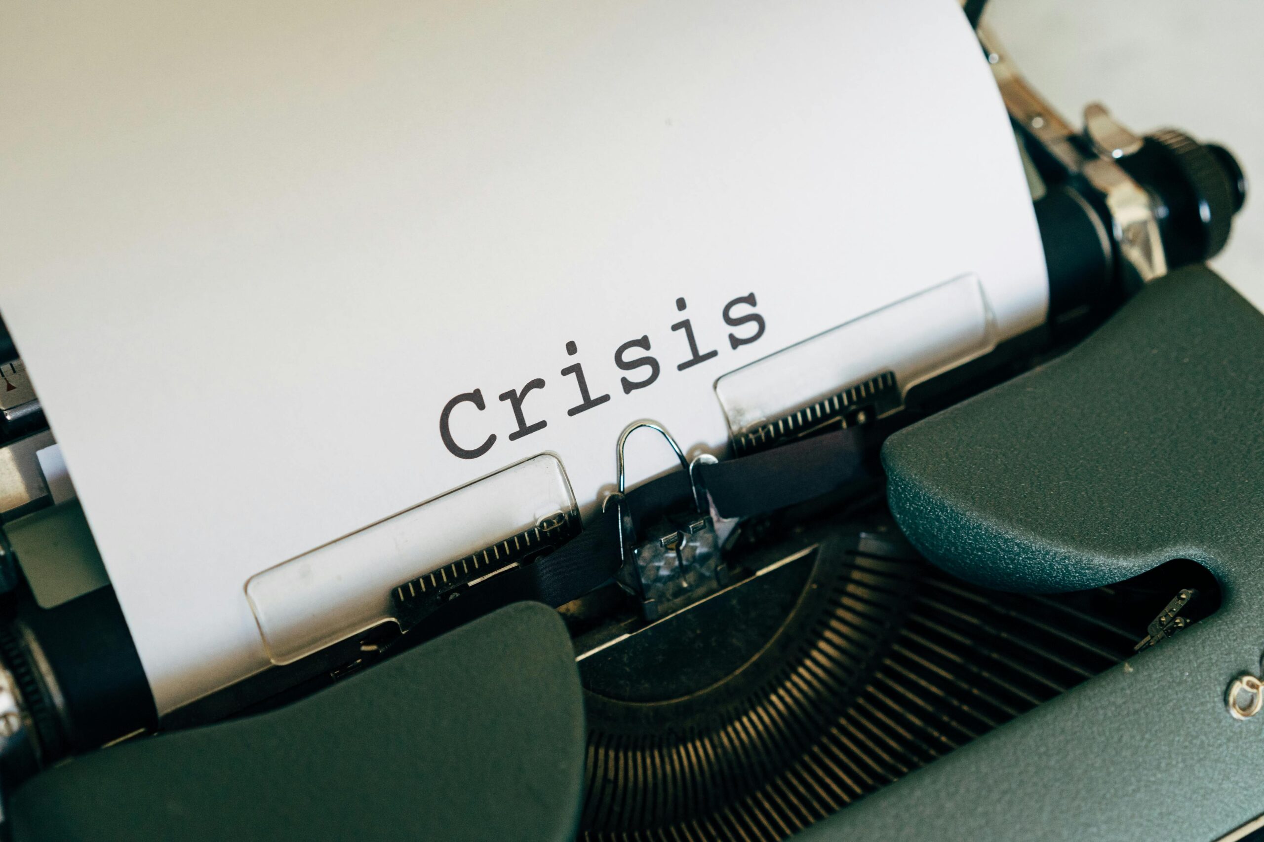 A typewriter with a sheet of paper printed with the word 'Crisis'.
