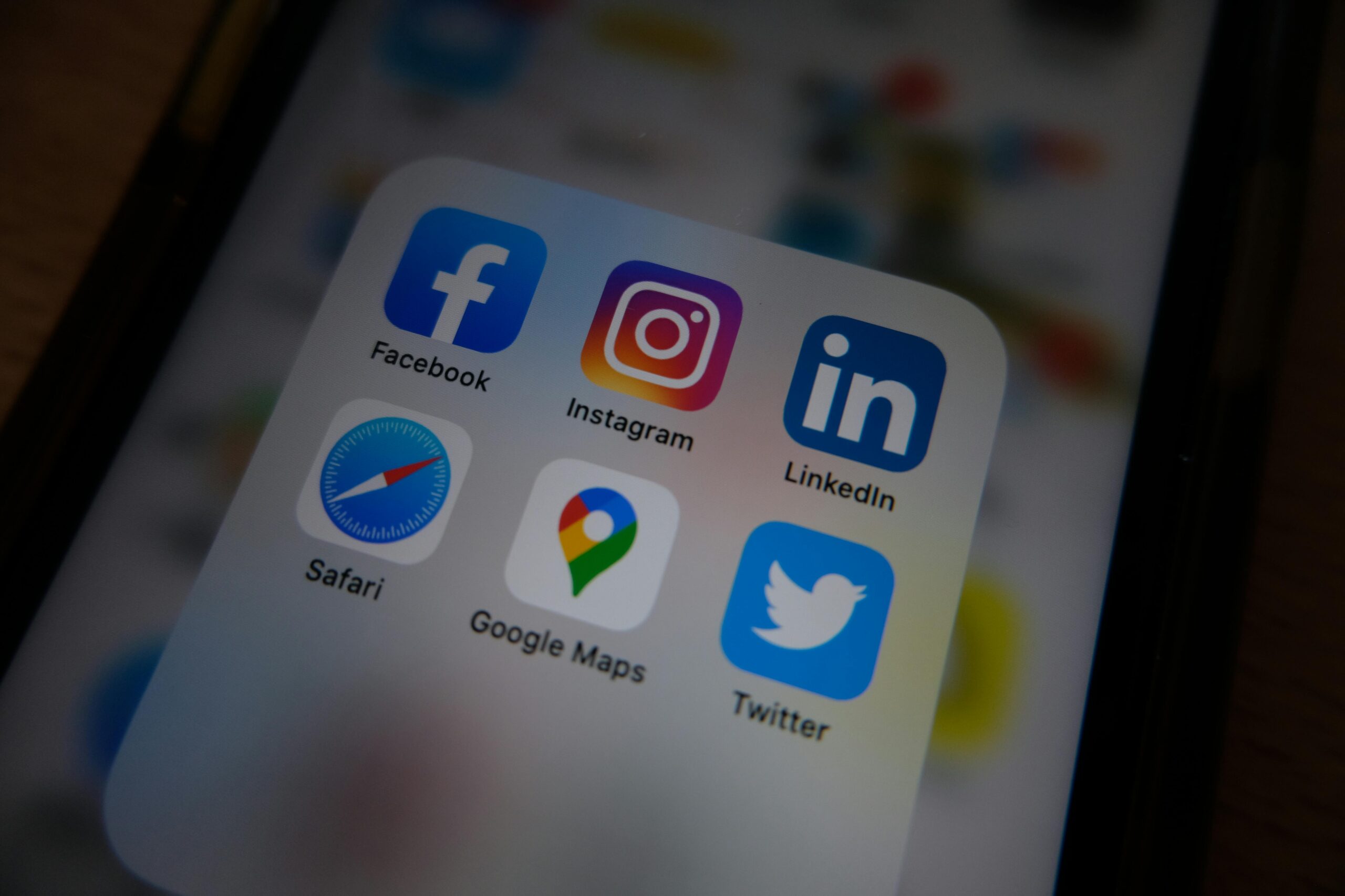 Close-up of a smartphone screen displaying social media app icons, including Facebook, Instagram, LinkedIn, Twitter, and others.