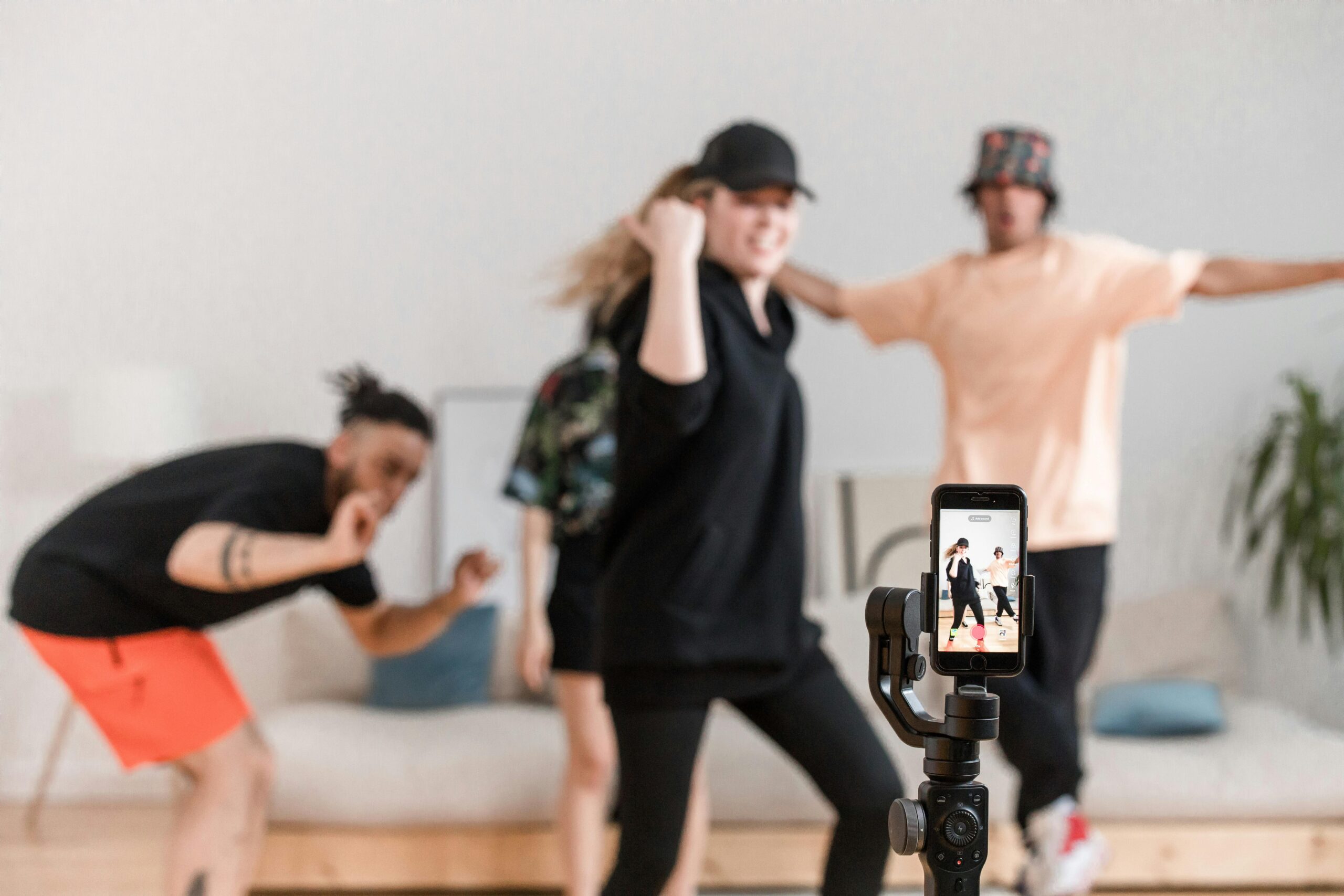 Three individuals dancing enthusiastically as a smartphone records the lively moment.