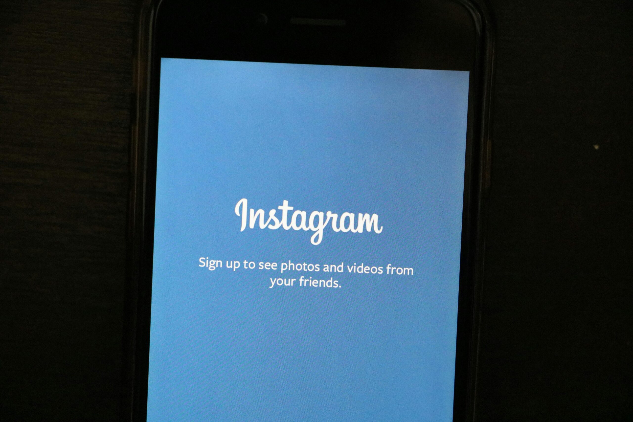 Smartphone displaying Instagram's sign-up screen with a blue background.