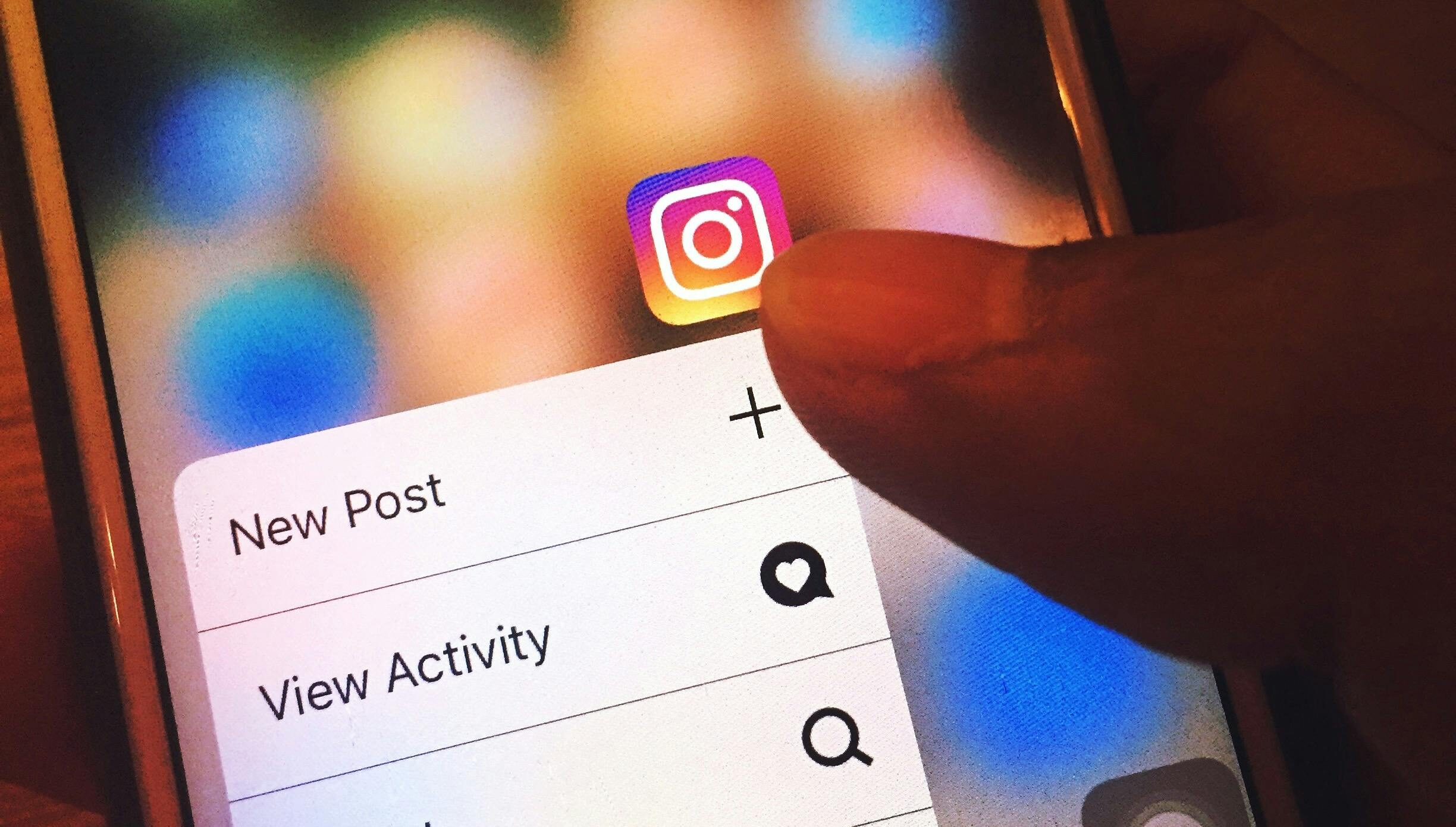 Close-up of a hand holding a smartphone with the Instagram app open.
