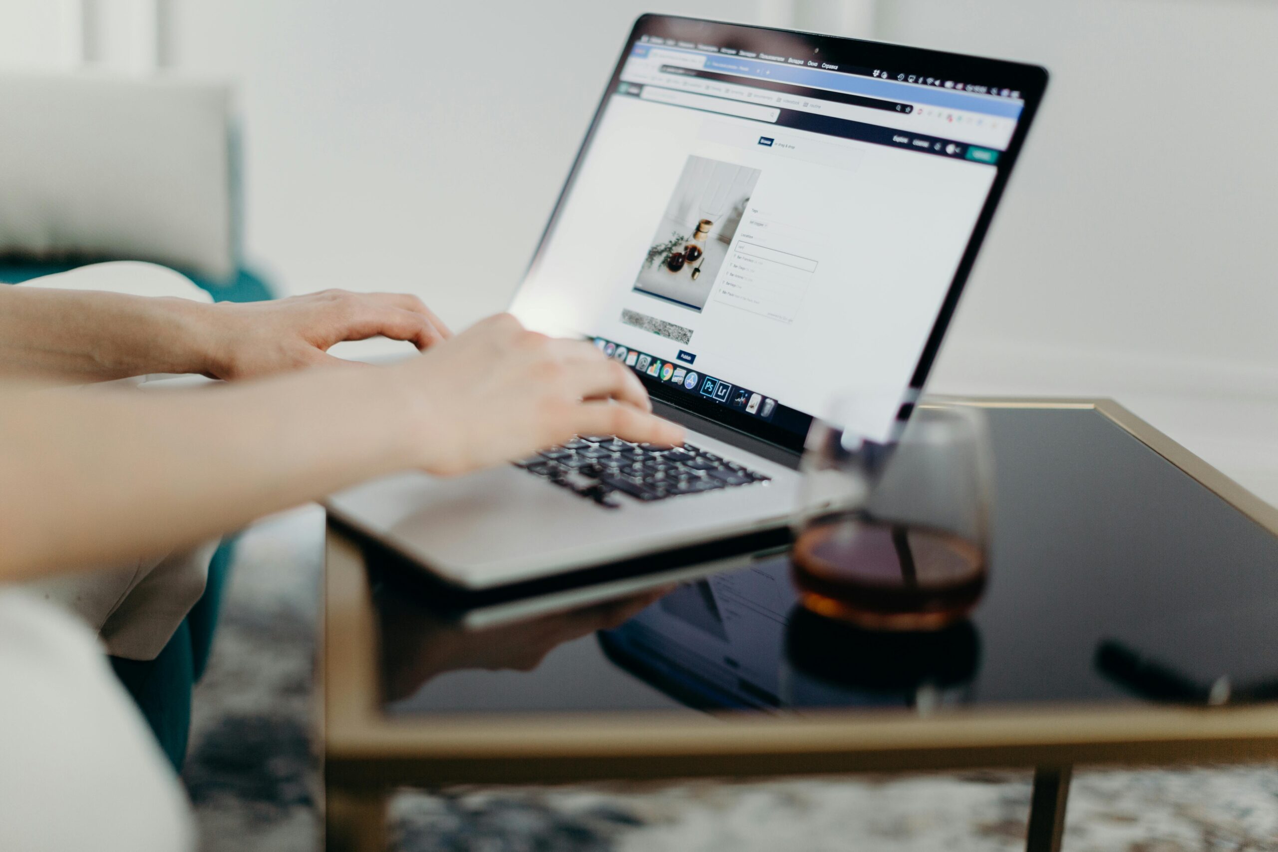 Close-up of hands typing on a laptop with a blog page open.