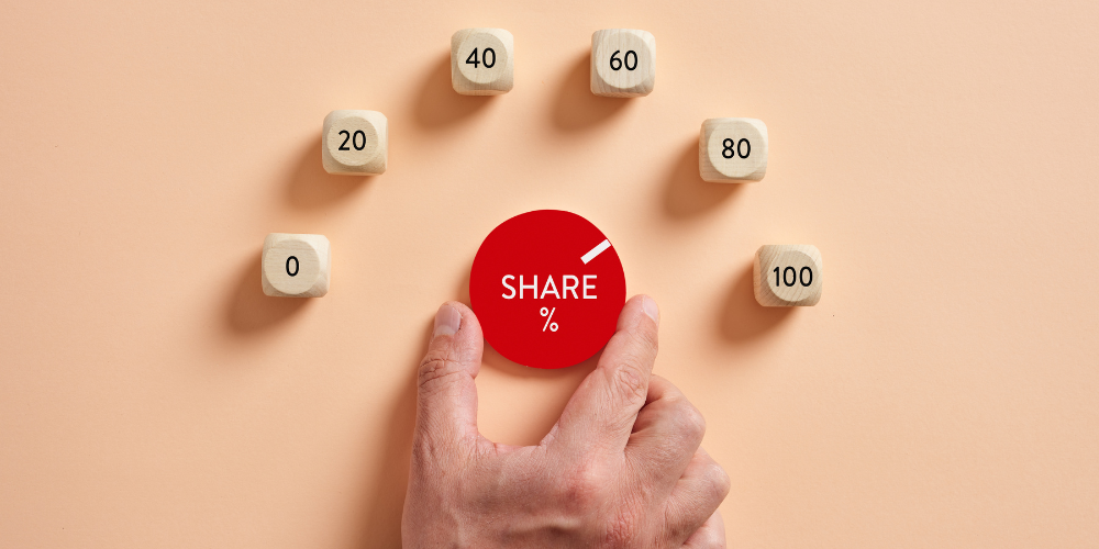 A hand arranging wooden cubes with percentage values next to a red disc labeled "SHARE %", representing market share or distribution metrics.