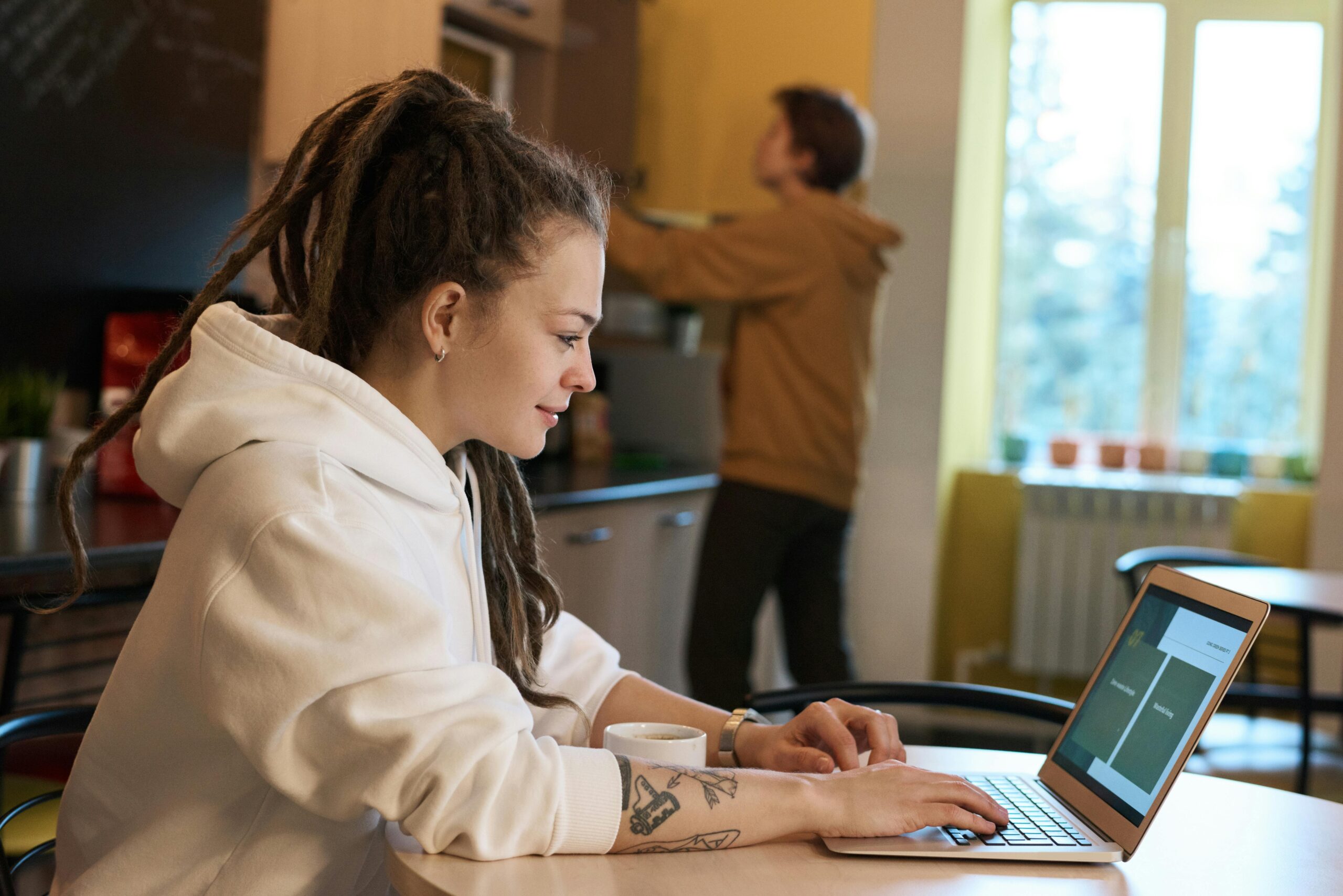 Woman working on freelance vs in-house content roles on her laptop in a casual setting.