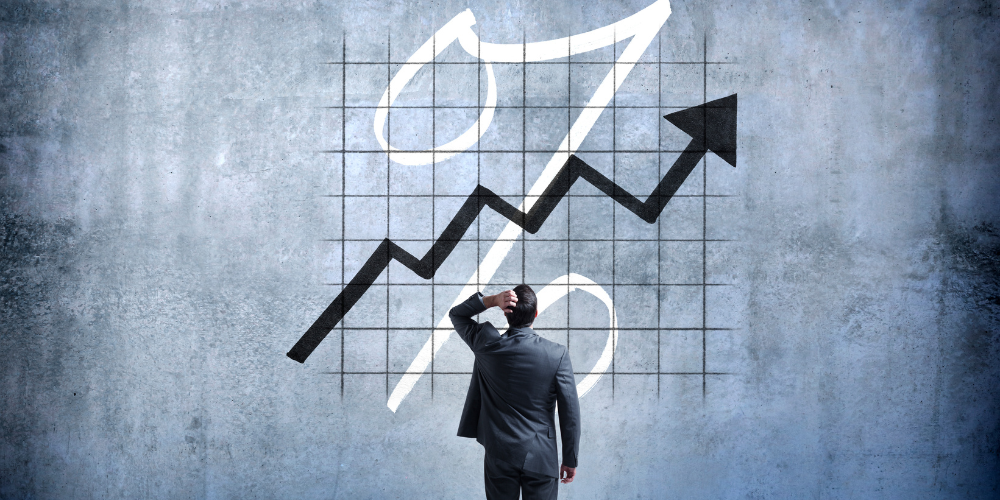 A man in a suit looking at a large upward-trending arrow graph painted on a concrete wall, symbolizing business growth or success.