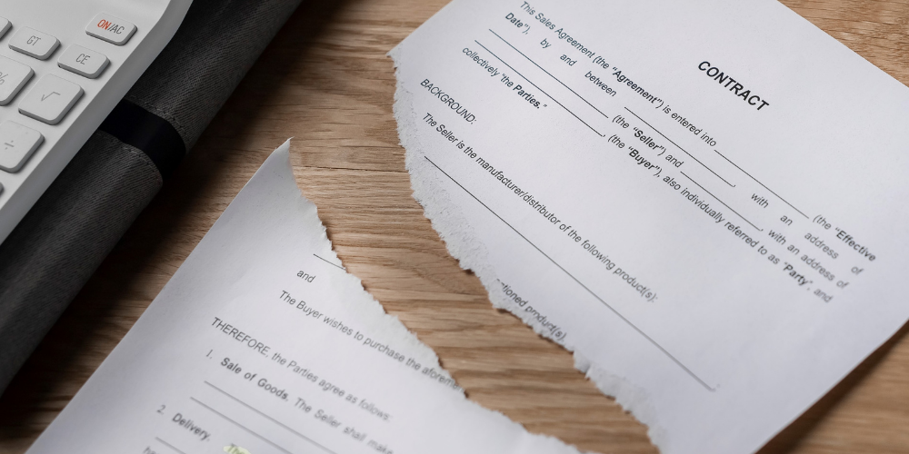 A close-up of a torn contract, indicating a breach, cancellation, or dispute over the agreement.