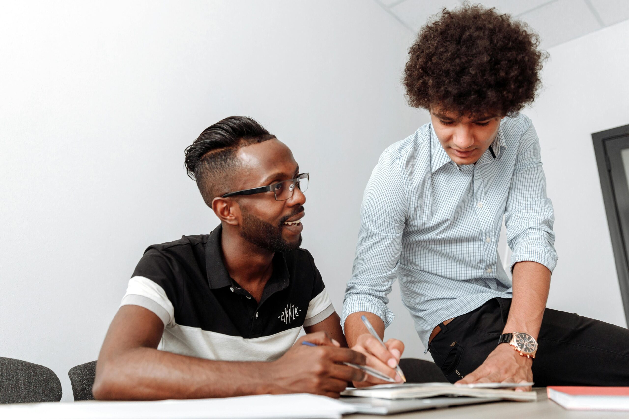 Two professionals discussing over a notebook in a modern office.