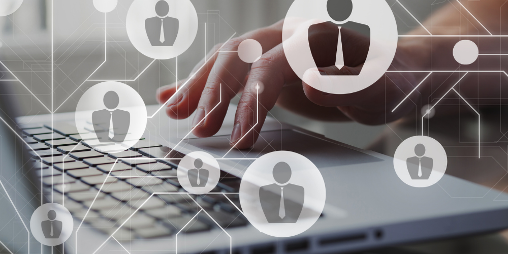 A hand over a laptop with digital icons representing user profiles, suggesting concepts of network, social media, or human resources management.