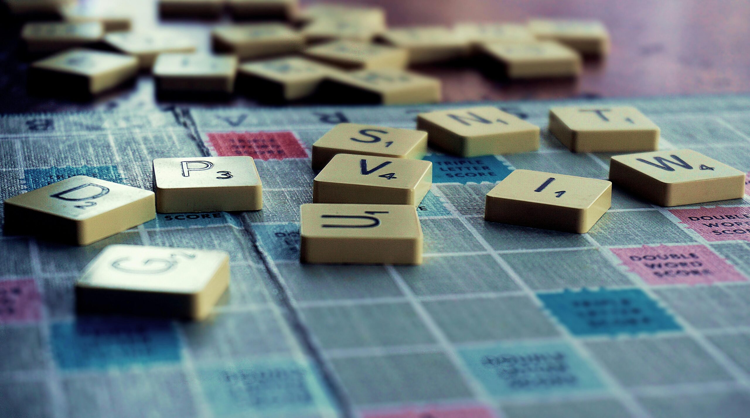 Scrabble game tiles scattered on a game board with a focus on letters forming the word 'POST'.