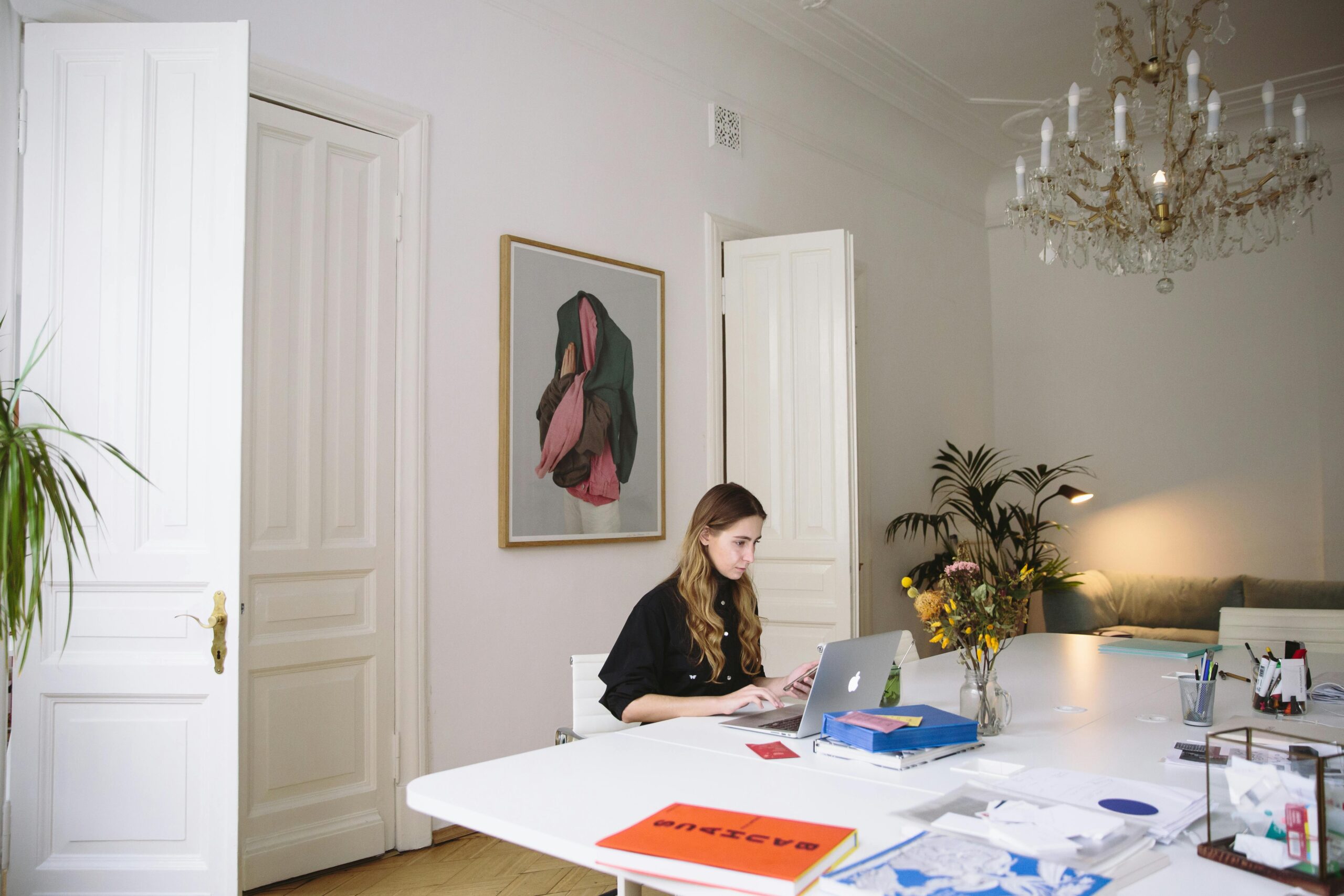 Designer working on a project in an elegant workspace with a classic chandelier above.