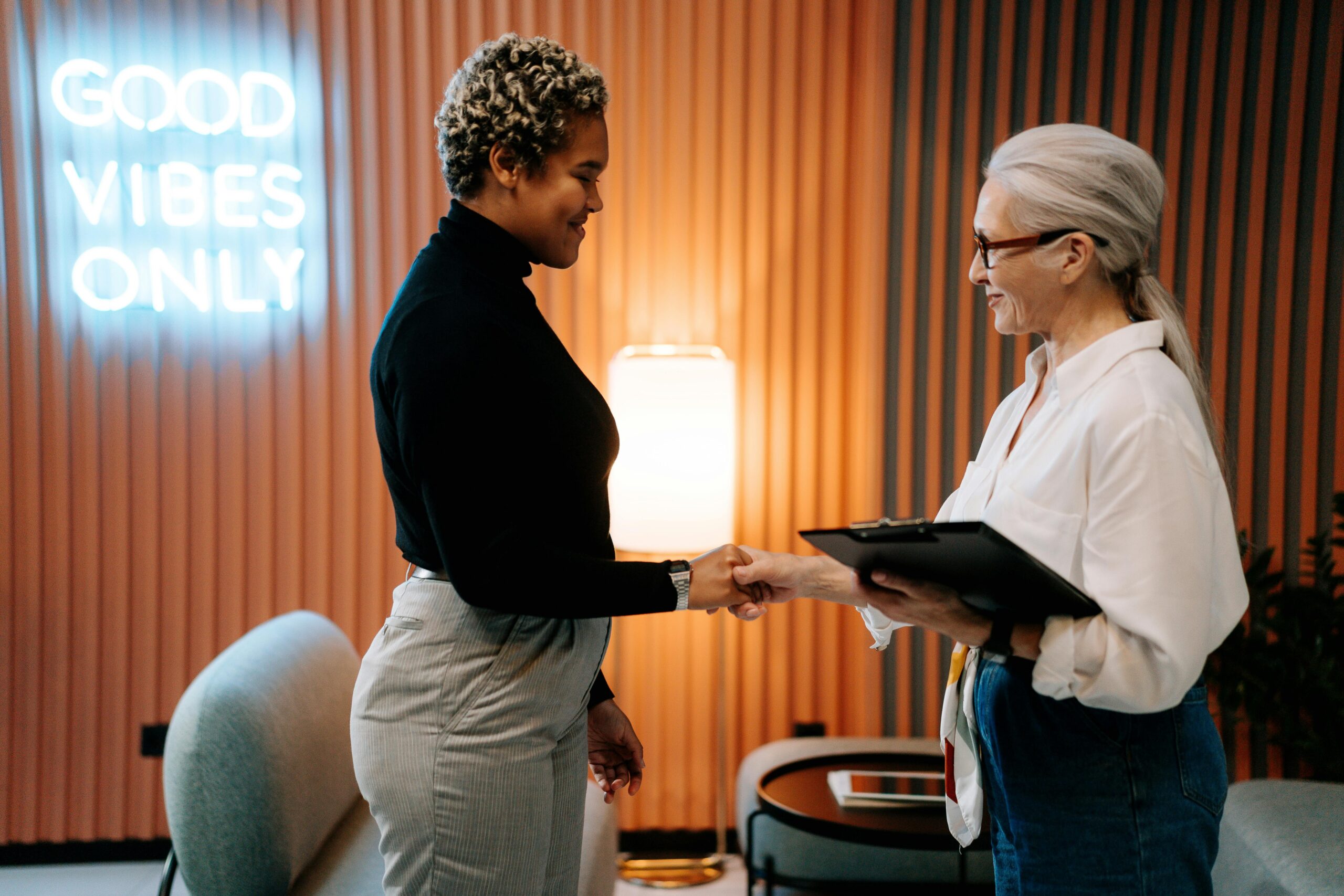 Recruiting manager greeting a candidate with a handshake in a modern office.