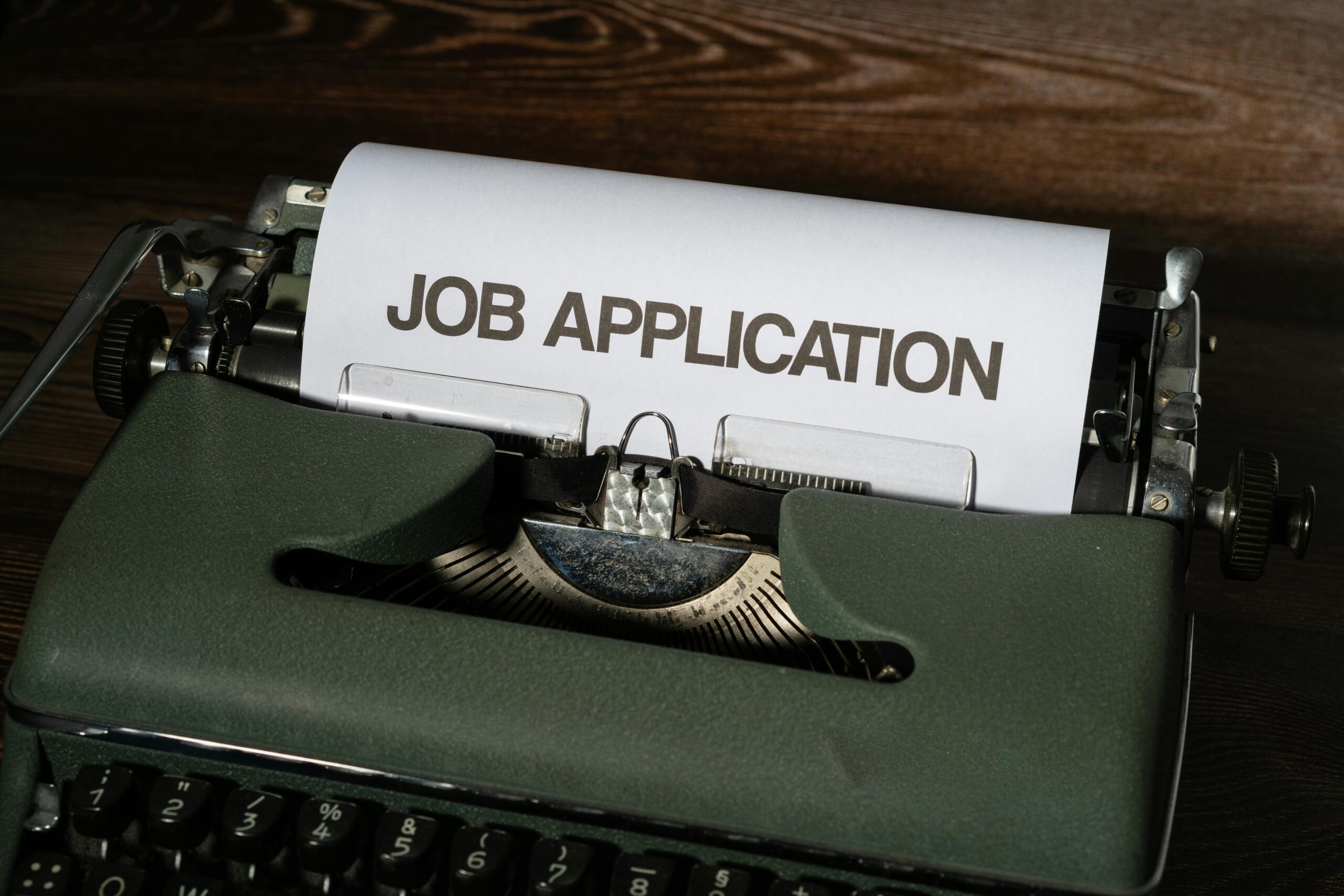 A typewriter with a paper titled "JOB APPLICATION" suggesting the use of a retro-themed professional summary generator.